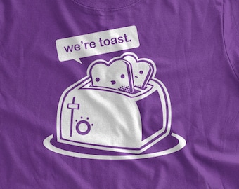 Könnte beinhalten: Lilafarbenes T-Shirt mit einer weißen Grafik eines Toasters mit zwei Brotscheiben darin. Der Text "we're toast." befindet sich über dem Toaster.