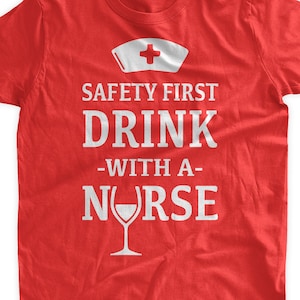 May include: Red t-shirt with a white graphic that says "Safety First Drink -With A- Nurse" with a wine glass icon.