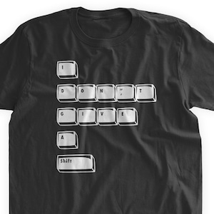 May include: Black t-shirt with a keyboard-style graphic. The design spells out "I DON'T GIVE A SHIFT" using white keyboard keys. A humorous and tech-inspired apparel item.