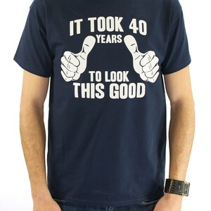 May include: A navy blue t-shirt with white text that reads "It took 40 years to look this good" with two white thumbs up on either side of the text.