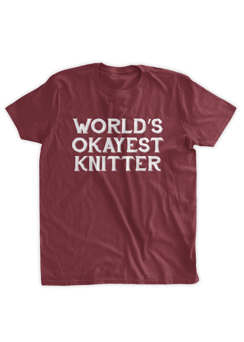 May include: A maroon t-shirt with the text "WORLD'S OKAYEST KNITTER" in white.