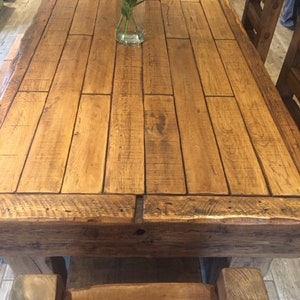 May include: A large, rectangular wooden dining table with a natural finish. The tabletop is constructed from planks of wood, and the table has a rustic, farmhouse style. The table is approximately 72 inches long and 40 inches wide.