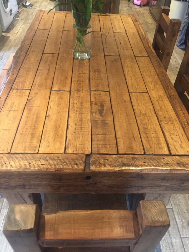 May include: A large, rectangular wooden dining table with a natural finish. The tabletop is constructed from planks of wood, and the table has a rustic, farmhouse style. The table is approximately 72 inches long and 40 inches wide.