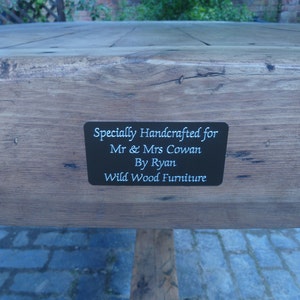 May include: A wooden table with a black plaque that reads "Specially Handcrafted for Mr. & Mrs. Cowan By Ryan Wild Wood Furniture".