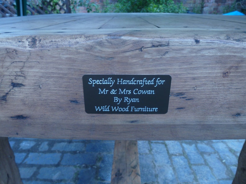 May include: A wooden table with a black plaque that reads "Specially Handcrafted for Mr. & Mrs. Cowan By Ryan Wild Wood Furniture".