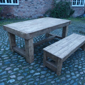 May include: A rustic wooden table and bench set. The table has a rectangular top and a simple, sturdy design. The bench is made of the same wood and has a slightly weathered finish.