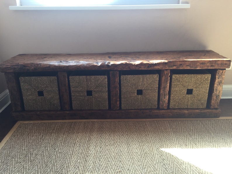 May include: A rustic wooden bench with four woven storage baskets. The bench has a natural wood finish and the baskets are a light brown color.
