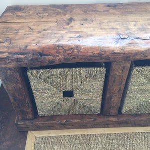 May include: Rustic wooden bench with three woven storage baskets. The bench has a natural wood finish and the baskets are a light brown color.