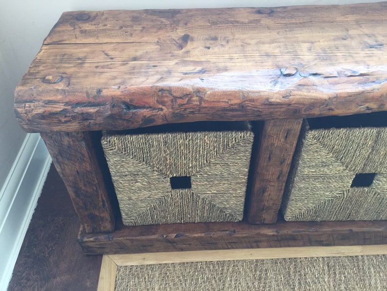 May include: Rustic wooden bench with three woven storage baskets. The bench has a natural wood finish and the baskets are a light brown color.