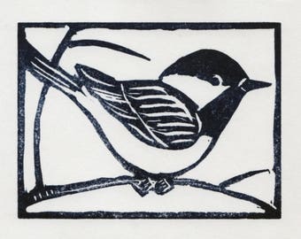 An original linocut print of a black-capped chickadee