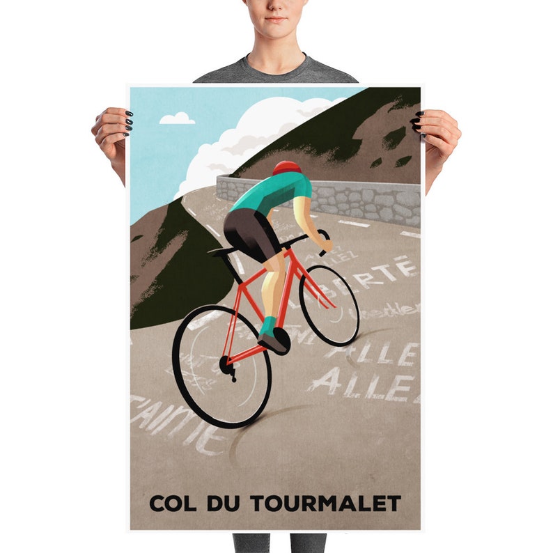 May include: A cyclist in a teal shirt and red helmet rides a red bicycle up a mountain road. The road is paved and has white lines painted on it. The cyclist is going uphill and the road is surrounded by mountains. The text "COL DU TOURMALET" is written in black at the bottom of the image.