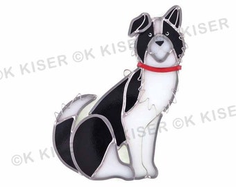 May include: A stained glass depiction of a black and white border collie dog sitting with a red collar. The dog is looking directly at the viewer.
