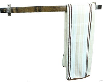 May include: A rustic towel rack made from a piece of reclaimed wood, with metal brackets. A striped towel in shades of beige, brown, and white hangs from the rack. The towel has vertical stripes and a brown border.
