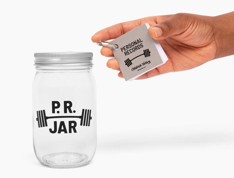 PR Jar™ for Personal Records, Weightlifting, Powerlifting, Crossfit. Jar is clear. Design is black. Coin slot lid is silver. Notepad included. The PR Jar™ is an original FitFizz creation that makes an excellent gift for yourself or any lifter.