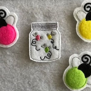 May include: Four felt appliques of fireflies and a jar with fireflies inside. The fireflies are in pink, yellow, and green. The jar is white with black stitching.