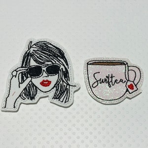 May include: Two embroidered iron-on patches. One features a black and white illustration of a woman wearing sunglasses. The other features a white mug with the text "Swiftea" in black cursive.