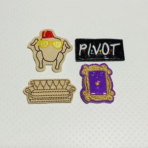 May include: Four embroidered iron-on patches featuring Friends TV show themes. The patches are beige, purple, black, and brown. The patches feature a turkey wearing sunglasses, a couch, a purple door, and the word "PIVOT" in black letters.