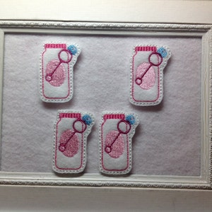 May include: Four white felt appliques shaped like jars with pink and blue embroidery. Each jar has a pink ball inside and a blue bubble wand on top.