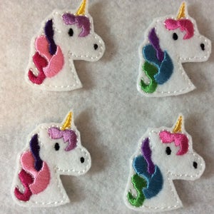 May include: Four felt unicorn head appliques in different color combinations. Each applique features a white unicorn head with a gold horn, purple mane, and a colorful mane and tail.