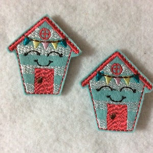 May include: Two blue and red felt appliques shaped like houses with a smiling face, a red door, and a string of colorful flags.
