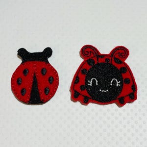 May include: Two felt ladybug appliques. One is a simple red ladybug with black spots. The other is a red ladybug with black spots and a smiling face.