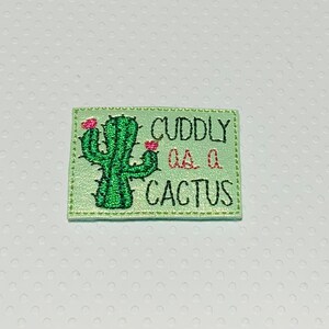 May include: A green embroidered patch with a cactus and the text "CUDDLY AS A CACTUS".