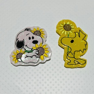 May include: Two embroidered iron-on patches featuring cartoon characters. One patch is white with a cartoon dog holding sunflowers. The other patch is yellow with a cartoon bird holding a sunflower.