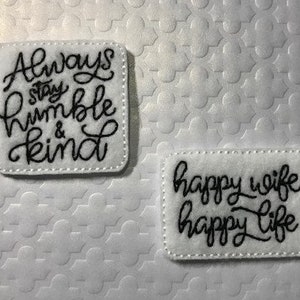 May include: Two white felt patches with black embroidered text. The first patch says "Always stay humble & kind". The second patch says "Happy wife happy life".
