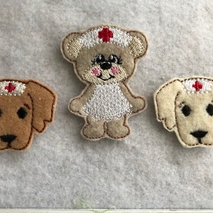 May include: Three felt appliques of a bear, a dog, and a dog wearing a nurse's hat with a red cross. The bear and one dog are beige, and the other dog is brown.