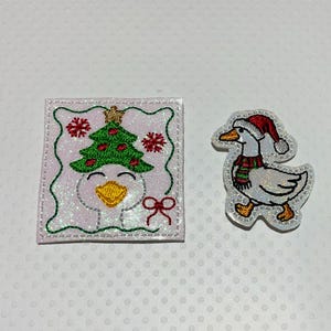 May include: Two embroidered patches featuring a white goose. One square patch shows a goose head wearing a green Christmas tree with a gold star, red snowflakes, and a red bow. The second patch is a goose wearing a red Santa hat and scarf.
