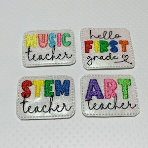 May include: Four white, sparkly, embroidered patches with colorful letters. The patches read "Music Teacher", "Hello First Grade", "STEM Teacher", and "Art Teacher".