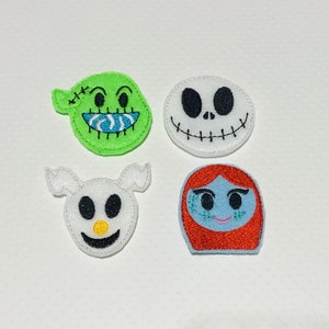 May include: Four felt appliques featuring characters from the Nightmare Before Christmas. The appliques are green, white, white, and orange. The characters are Jack Skellington, Sally, Zero, and Oogie Boogie.