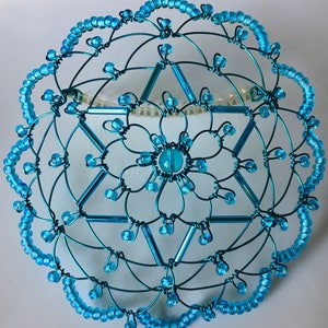May include: A turquoise blue wire kippah with a six-pointed star design and a beaded border.