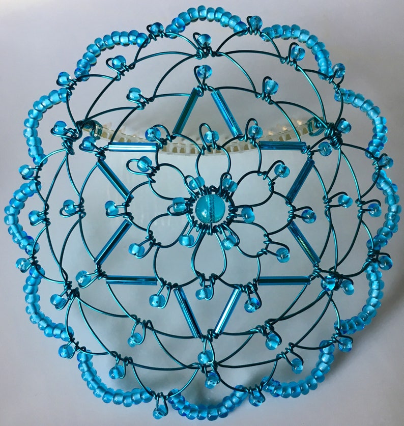 May include: A turquoise blue wire kippah with a six-pointed star design and a beaded border.