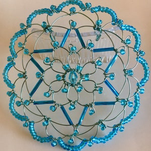 May include: A turquoise blue wire and bead kippah with a six-pointed star design. The kippah is attached to a comb for easy wearing.