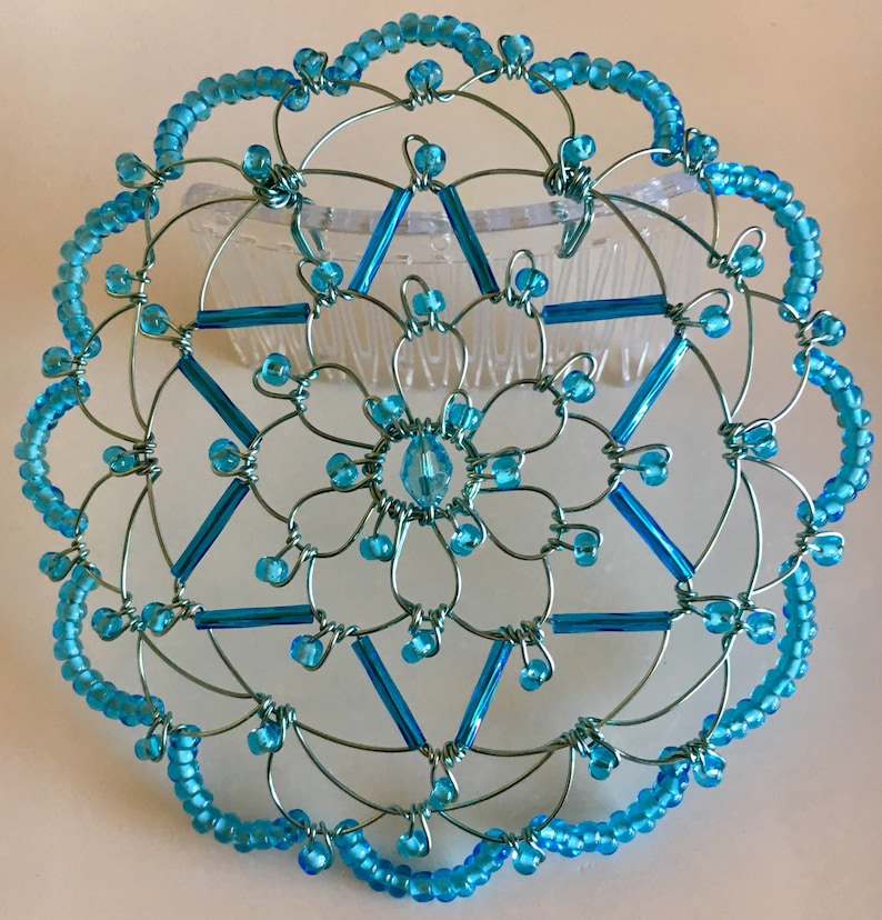 May include: A turquoise blue wire and bead kippah with a six-pointed star design. The kippah is attached to a comb for easy wearing.
