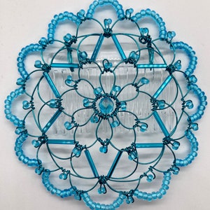 May include: A turquoise blue wire hair comb with a crystal center and a beaded border.