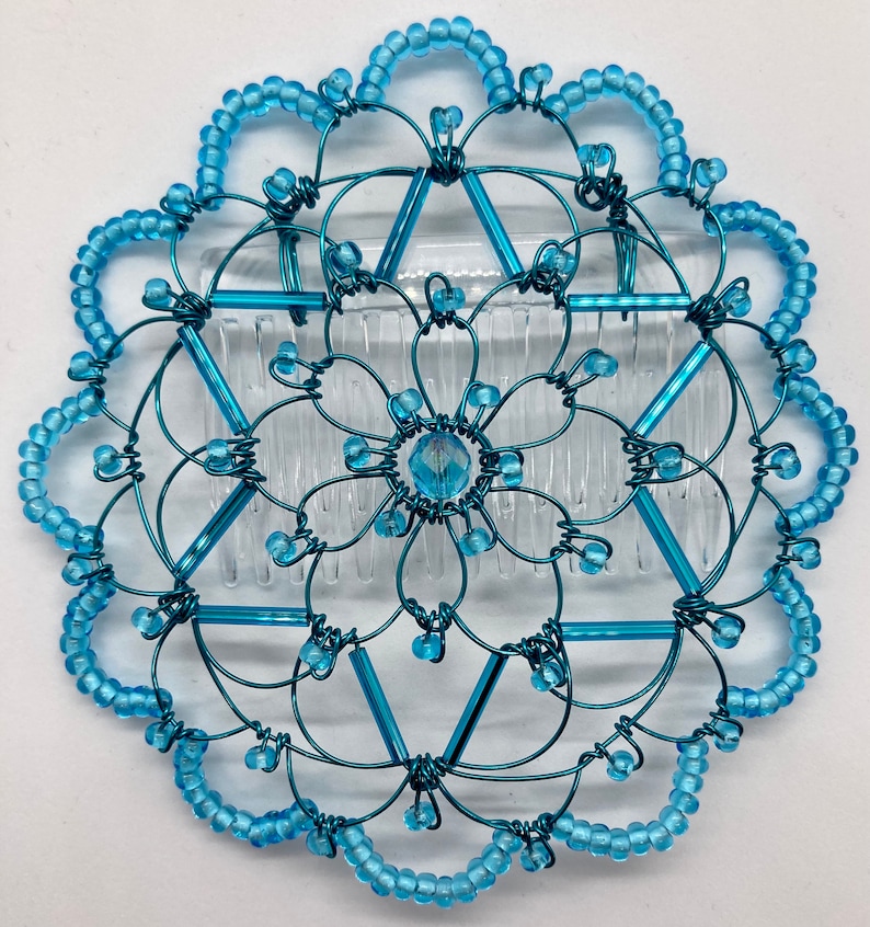 May include: A turquoise blue wire hair comb with a crystal center and a beaded border.