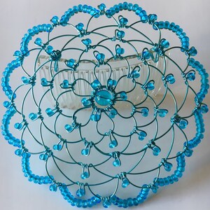 May include: A turquoise blue wire hair comb with a beaded design. The comb is decorated with turquoise blue beads and has a floral pattern.