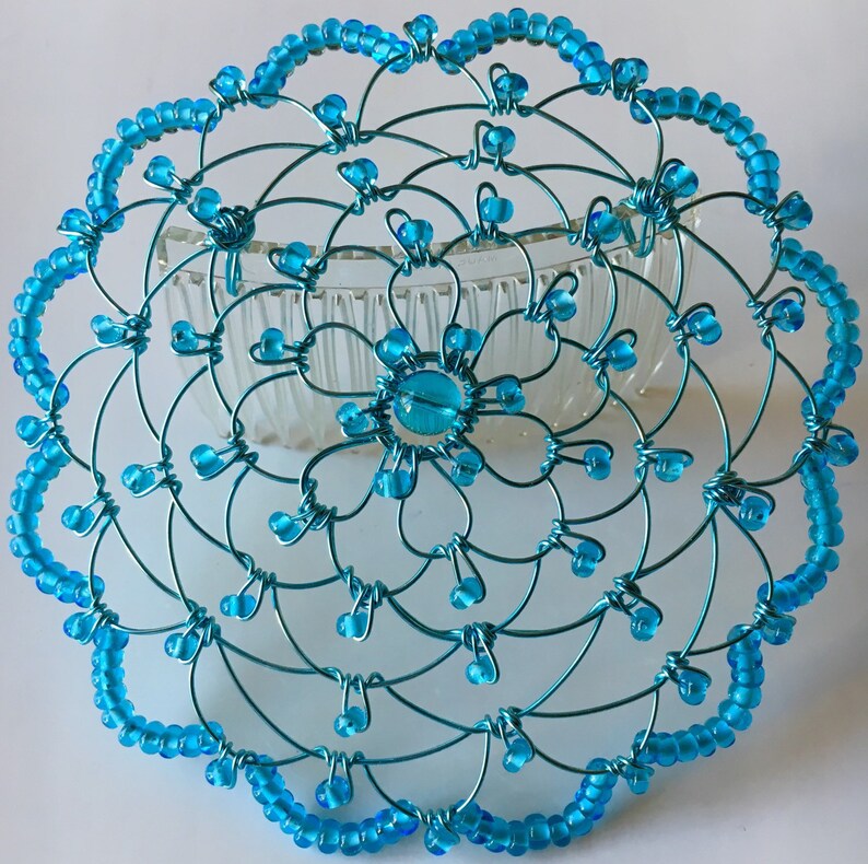 May include: A turquoise blue wire hair comb with a beaded design. The comb is decorated with turquoise blue beads and has a floral pattern.