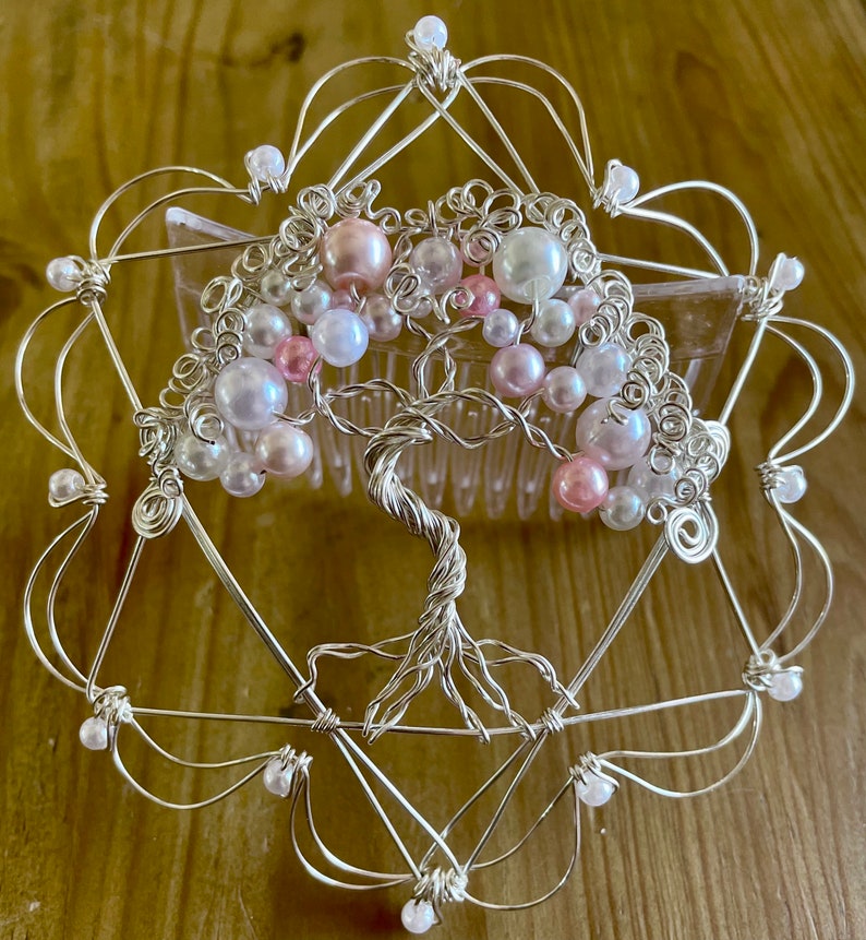 May include: A silver wire tree of life hair comb with pink and white pearl beads. The comb is in the shape of a heart with a wire frame.