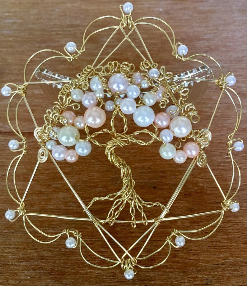 May include: A gold wire tree of life sculpture with pink, white, and cream pearls. The tree is surrounded by a gold wire frame in the shape of a star of David.