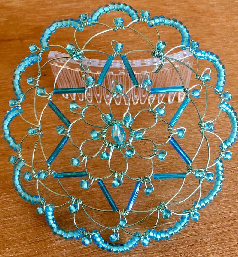 May include: A turquoise blue wire hair comb with a star of David design. The comb is decorated with small turquoise blue beads and larger turquoise blue beads. The comb is attached to a clear plastic comb.