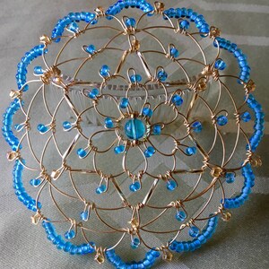May include: A gold wire kippah with a blue bead border and a blue bead center.
