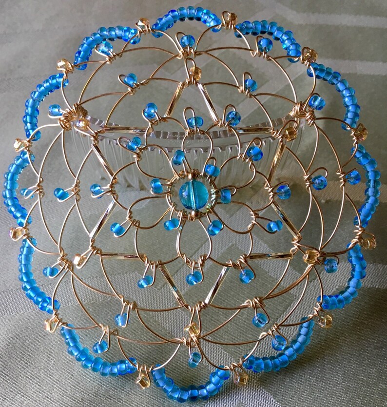May include: A gold wire kippah with a blue bead border and a blue bead center.