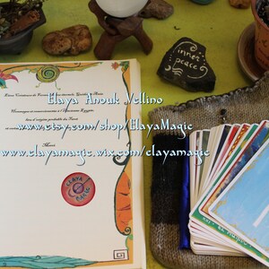 May include: A book with a certificate of formation for Elaya Anouk Wellino, a business that creates handmade items. The book is open to a page with the text "www.etsy.com/shop/ElayaMagic" and "www.elayamagic.wix.com/elayamagic". A deck of tarot cards is in a knitted bag.