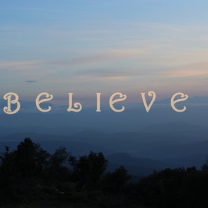 Peut inclure: Une citation motivante, "BELIEVE", est affichée dans une police stylisée sur fond de ciel bleu et de montagnes lointaines. Le ciel est bleu clair avec une touche de rose au loin, suggérant un lever ou un coucher de soleil.