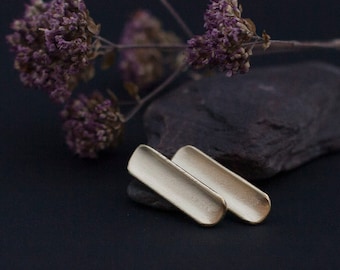 Stud earrings in brass with soft curving volume reflecting light nicely. Ear stud is in silver •