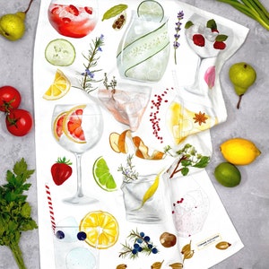 May include: White kitchen towel with a colorful illustration of various ingredients and cocktails. The illustration includes lemons, limes, berries, herbs, and ice. The text "Corinne Alexander" is printed in the bottom right corner.