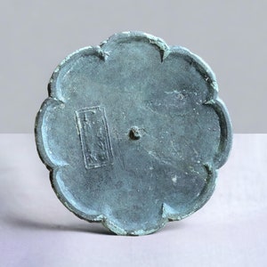 Może przedstawiać: Okrągła, zielona taca z brązu z falistym brzegiem i kwadratowym napisem na spodzie.